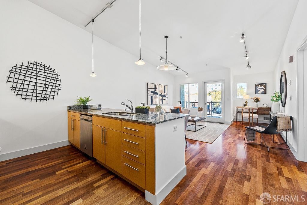 Open-plan kitchen with a wood-front island and granite countertop, opening onto a furnished living area and balcony.