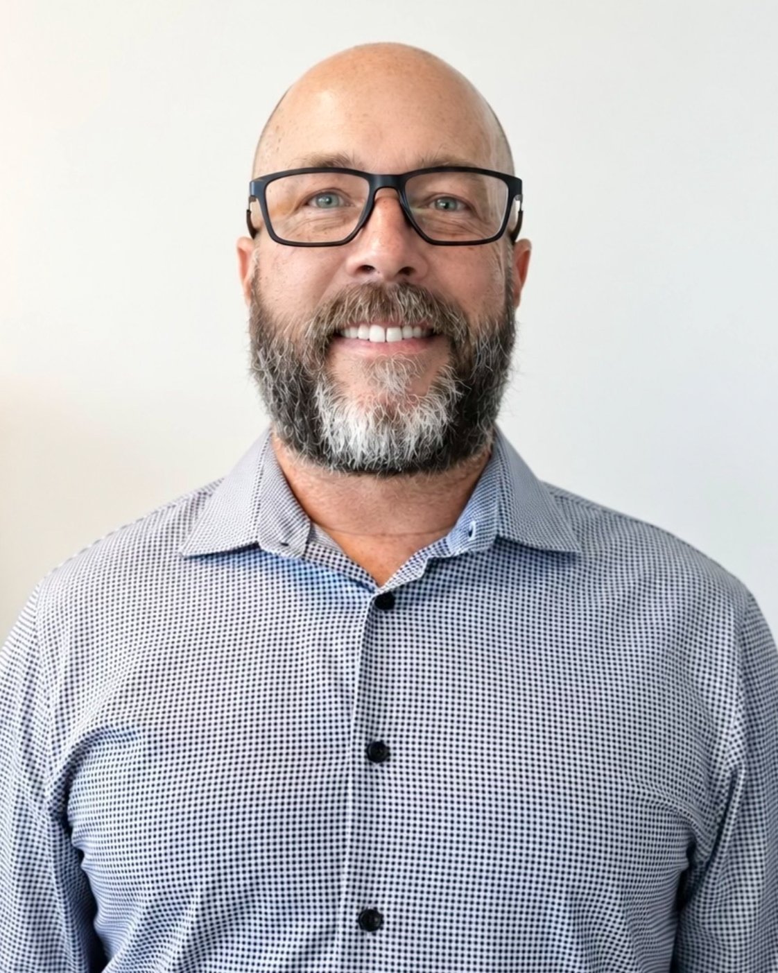 Brad Ferguson smiling in black glasses and a small-check shirt.