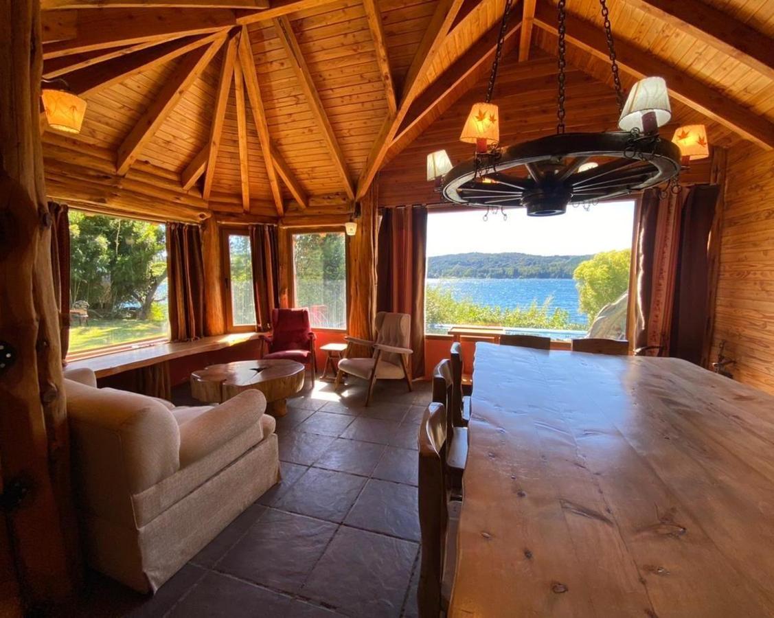 Furnished lake-view dining and living room beneath a vaulted timber ceiling.
