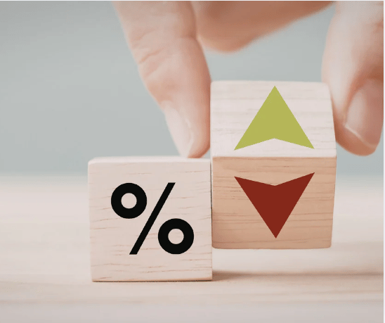 Wooden blocks show a percent sign beside green upward and red downward arrows as fingers move one block.