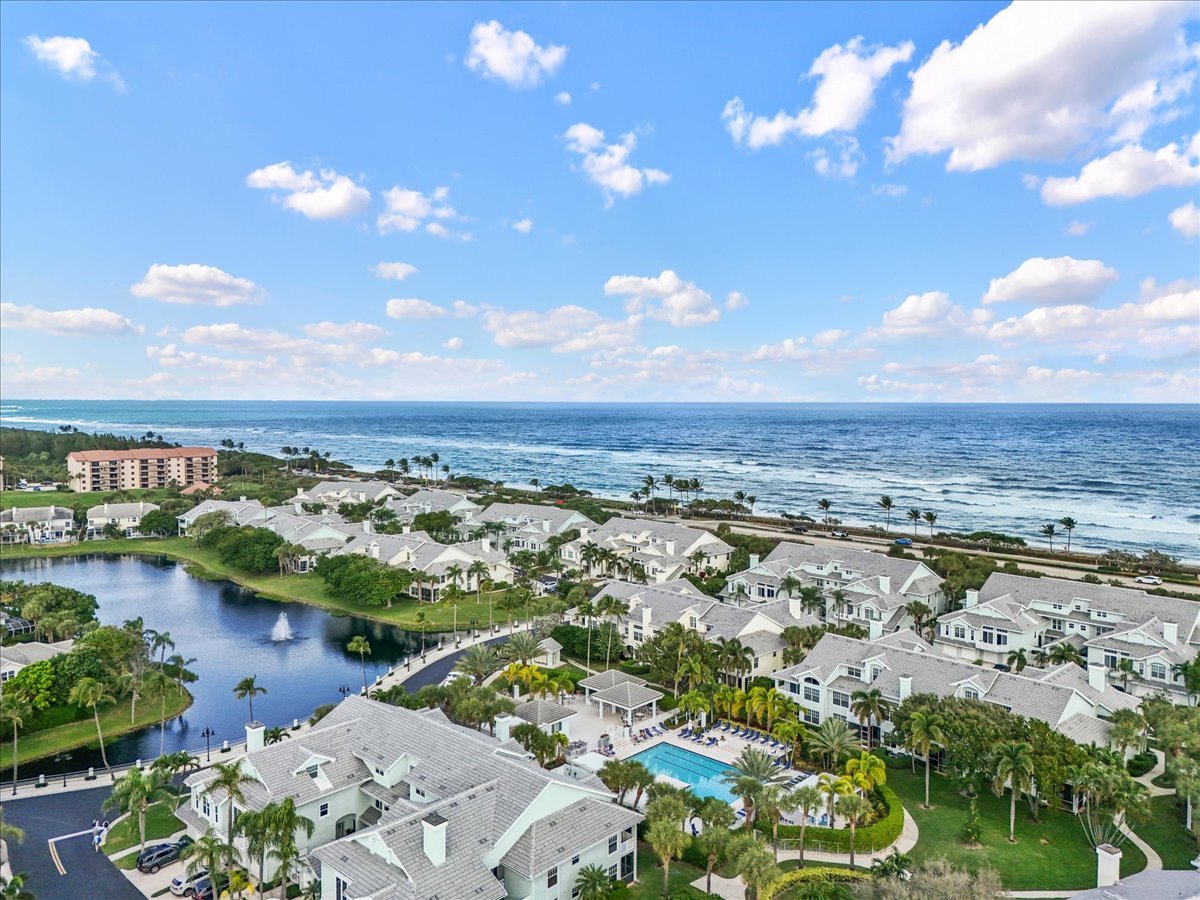 Aerial view of coastal condominium homes beside the ocean, with a lagoon and swimming pool.