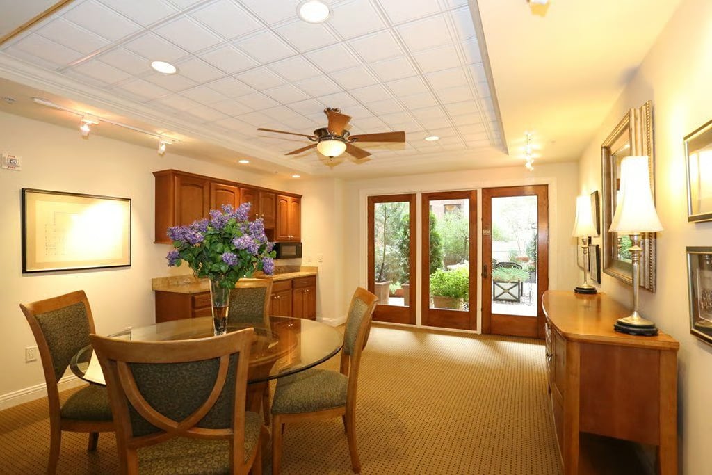 Dining room with a glass-top table, wood cabinetry, and French doors opening to a garden.