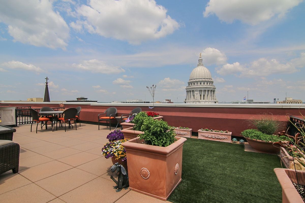 Rooftop terrace with flower planters and seating overlooking the Wisconsin State Capitol.