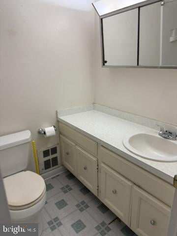 Bathroom with cream vanity, oval sink, mirrored cabinet, and patterned tile floor.