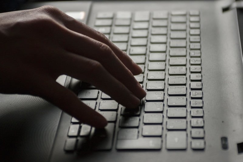 A hand typing on a laptop keyboard.