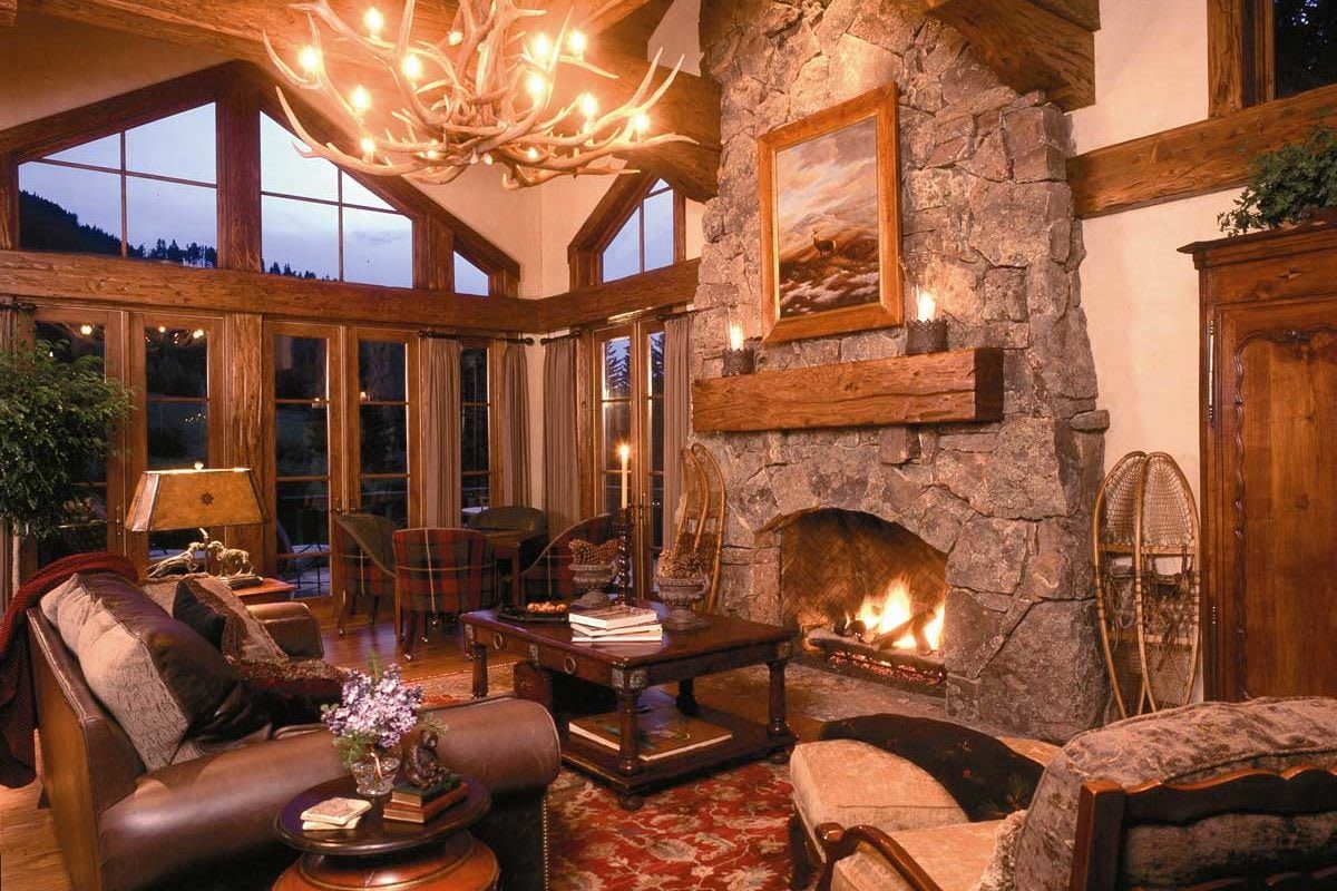 A rustic living room with a large stone fireplace