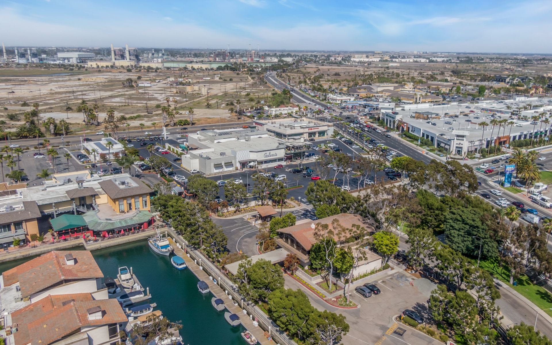 Aerial view of a marina canal with boats, homes, and a nearby shopping center.