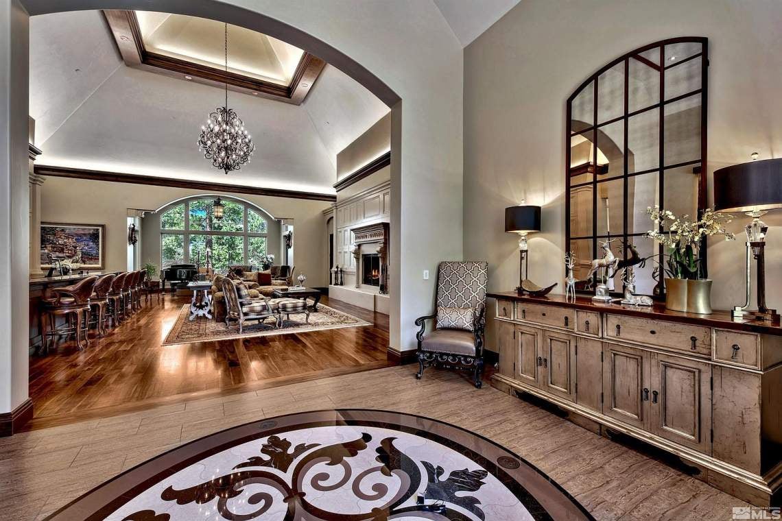 Formal living room with vaulted ceiling, arched windows, fireplace, and hardwood floors.