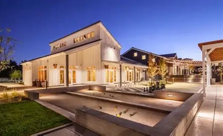 Modern Rancharrah Village building with glowing windows and a reflecting pool at dusk.