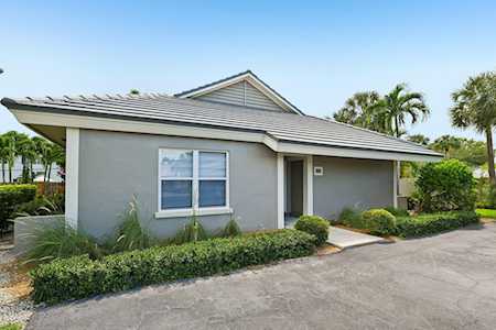 Single-story gray home with a low-pitched roof, landscaped front beds, and a paved driveway.