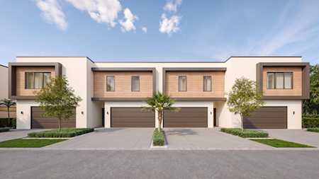 Modern attached homes with upper-level windows, private garages, and landscaped front lawns.