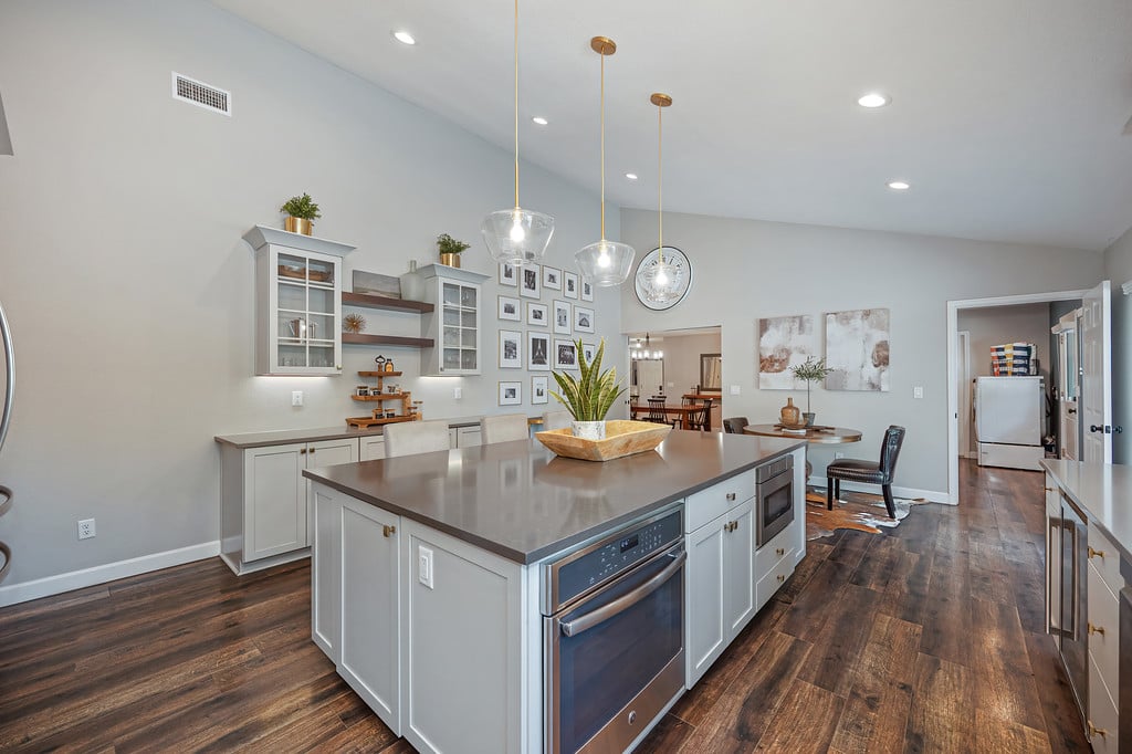 Spacious kitchen with a large island, dark wood floors, and pendant lights.