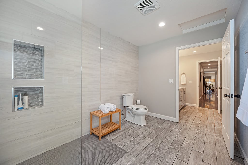 Bathroom with a glass walk-in shower, recessed niches, and wood-look tile flooring.