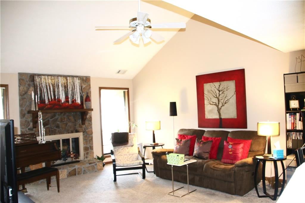 Furnished living room with a stone fireplace, vaulted ceiling, and brown sectional sofa.