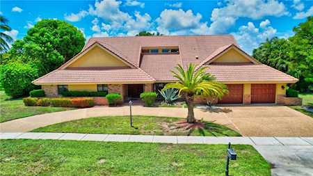 Single-story home with a broad tile roof, front lawn, palm tree, and double garage.