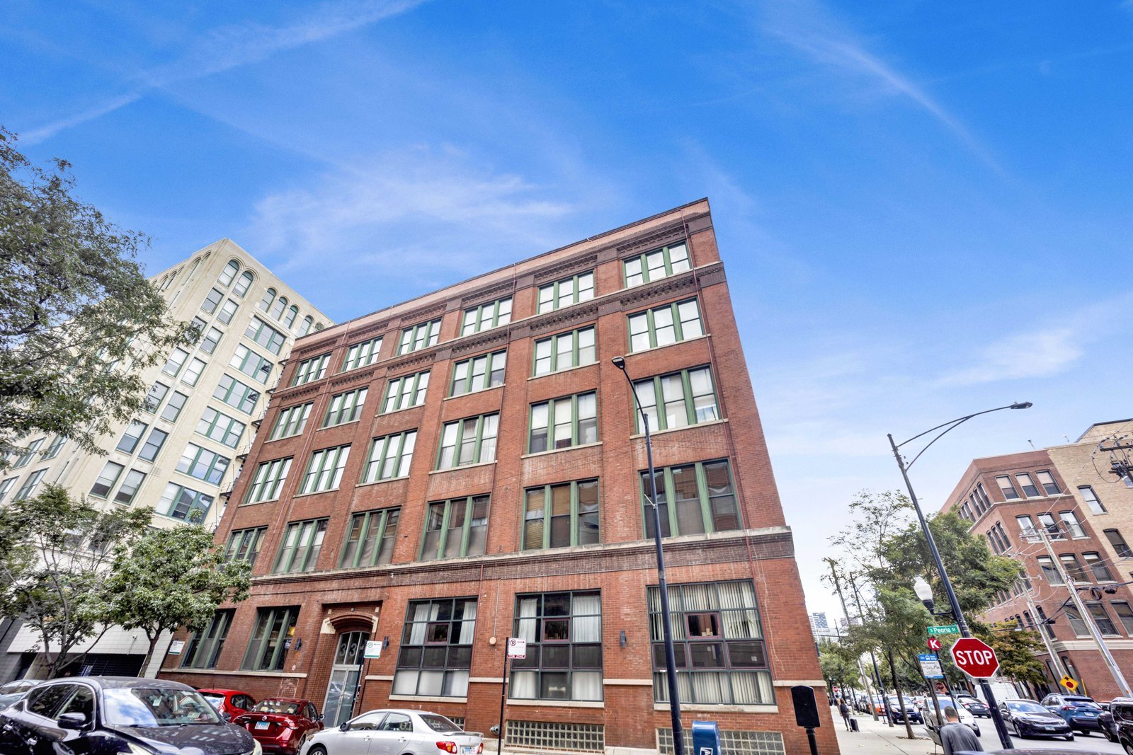 Red brick loft building on a tree-lined Chicago street, home to a condo listed by Dee Savic