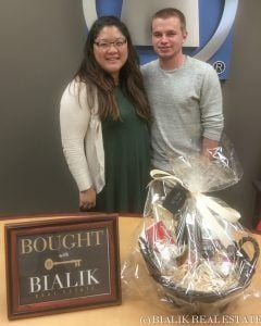 Tyler and Linsi celebrate their closing beside a framed Bialik sign and gift basket.