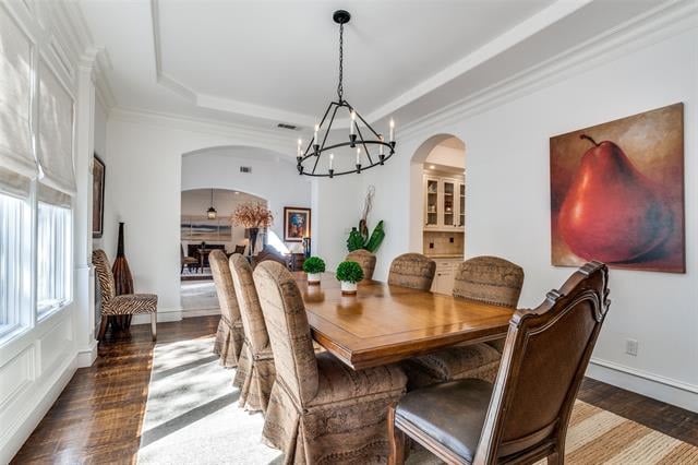 Formal dining room with a wooden table, upholstered chairs, and a black metal chandelier.