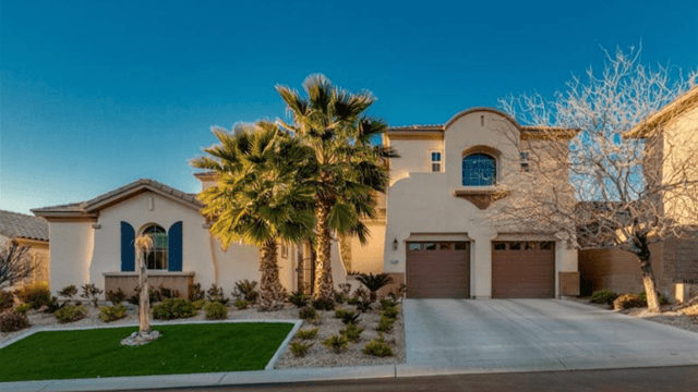 Two-story stucco home with double garage, palm trees, and landscaped front yard.