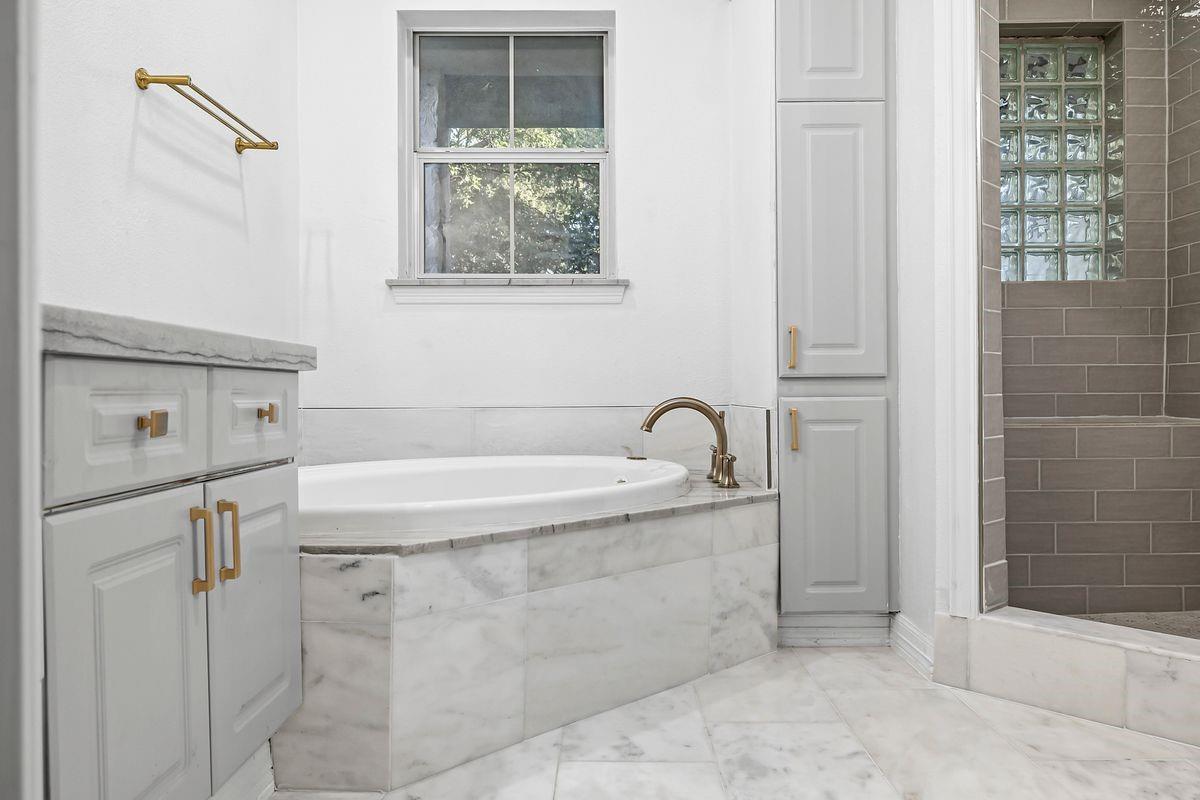 Primary bath soaking tub with marble surround and glass block window, Barton Hollow, Westlake, Austin.