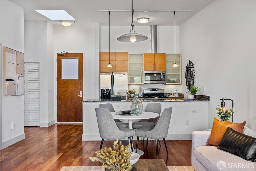 Open-plan kitchen and dining area with wood cabinetry, stainless steel appliances, and a round table.