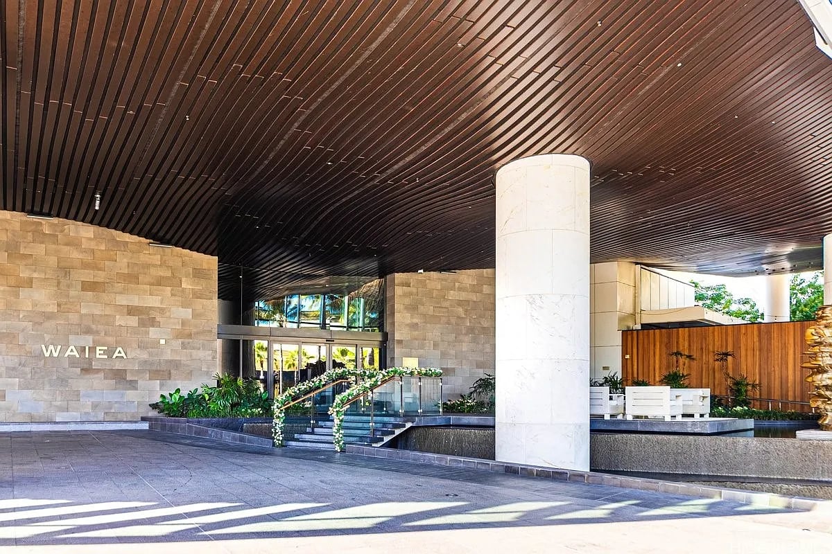 Waiea condominium entrance with a covered porte-cochère, stone walls, and landscaped steps.