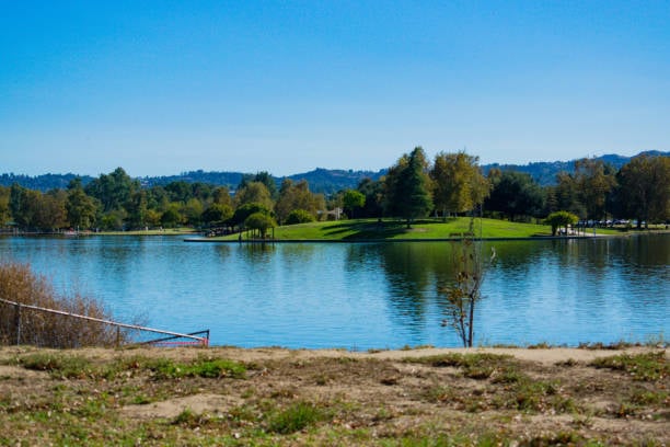Calm lake water at Anthony C. Beilenson Park in Lake Balboa, San Fernando Valley, with grassy peninsula and distant mountains