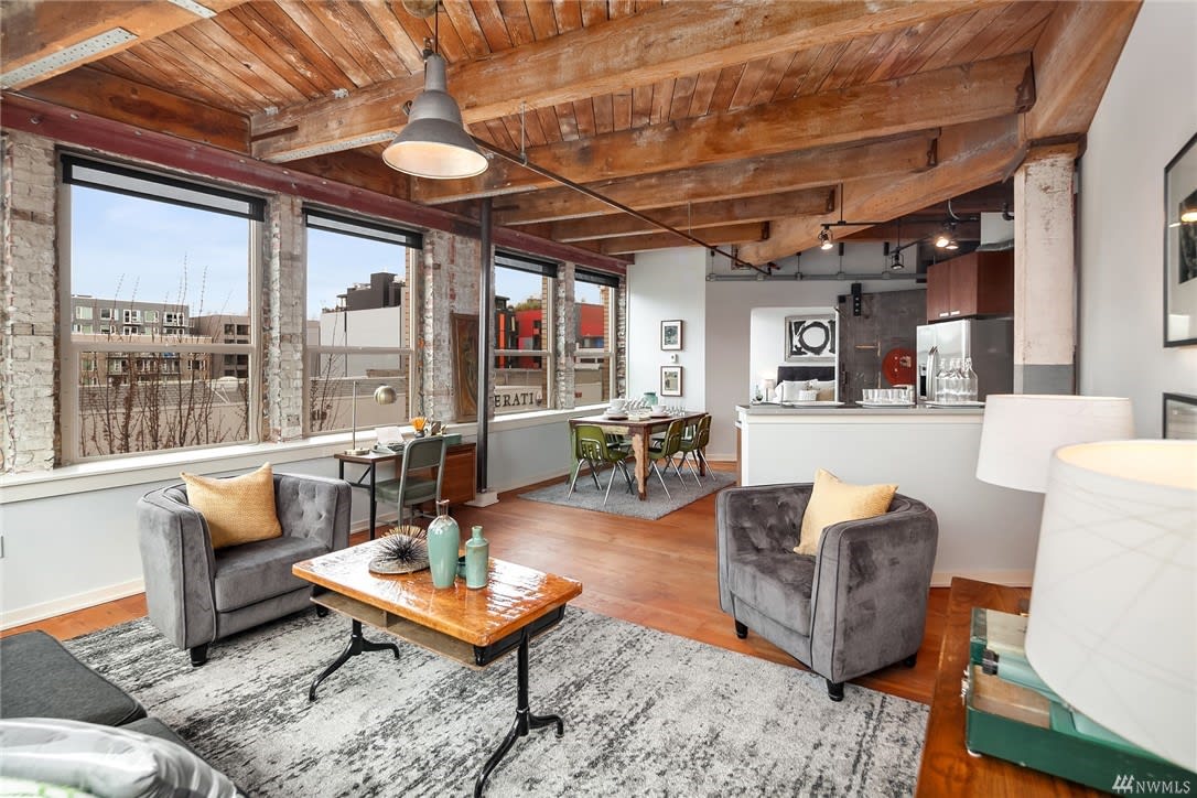 A charming living room with a large window and wooden beams, creating a cozy atmosphere.