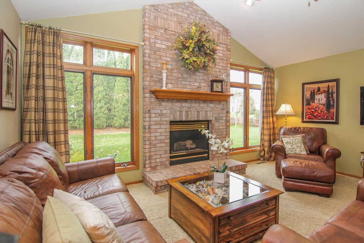 Living room with a tall brick fireplace, large windows, and leather seating.