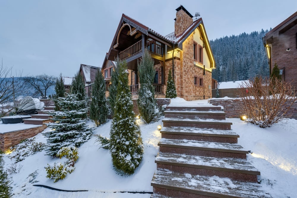 Charming wintery home with excellent curb appeal, featuring snow-covered landscaping, festive decorations, and a warm, welcoming atmosphere.