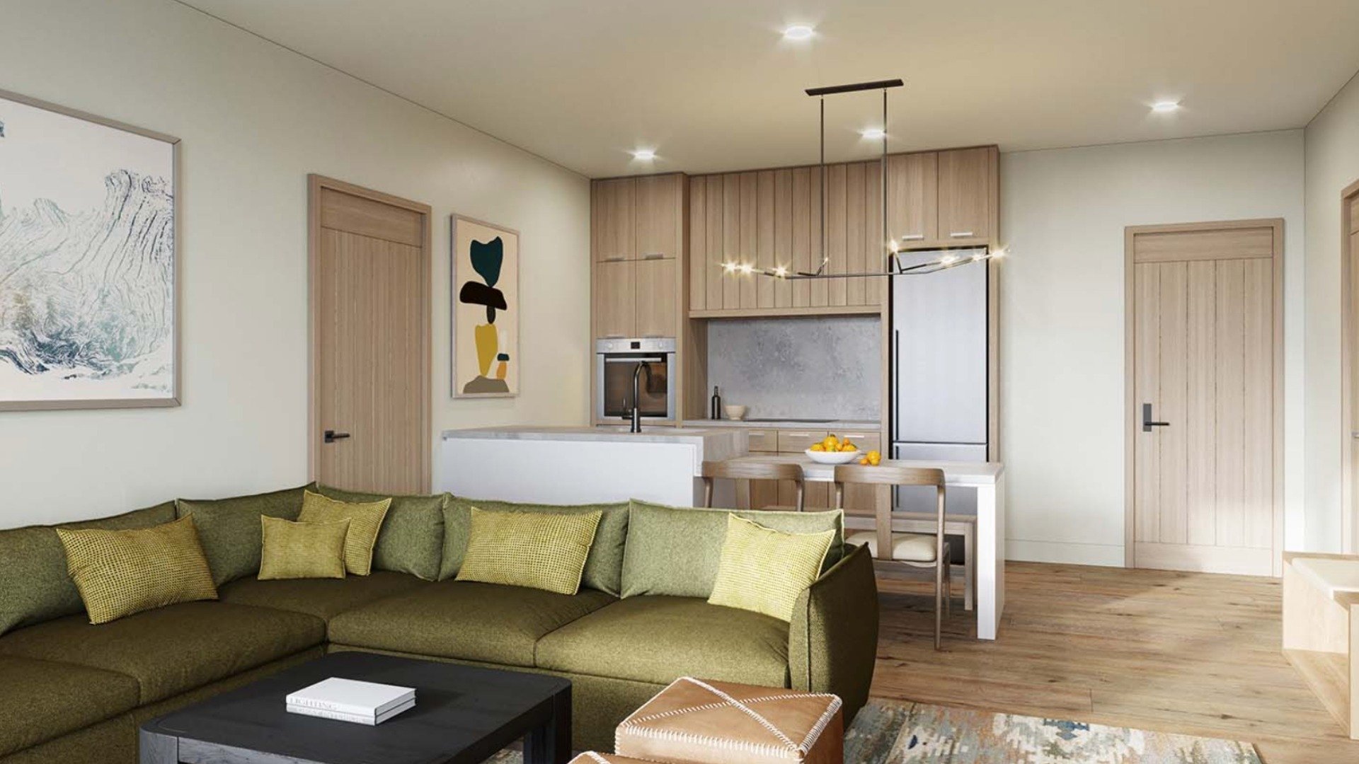 Open-plan lodge living room and kitchen with a green sectional and light wood cabinetry.