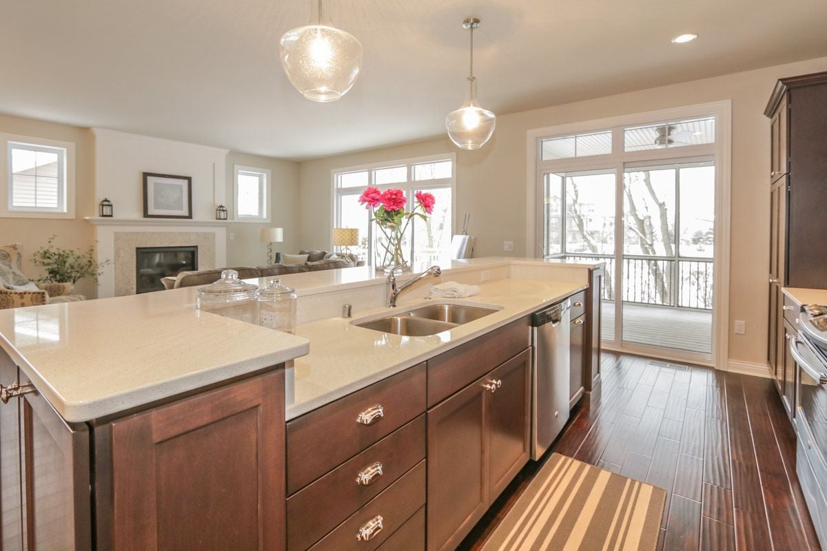 Open kitchen with a large stone island, dark wood cabinets, and glass doors to a snowy deck.