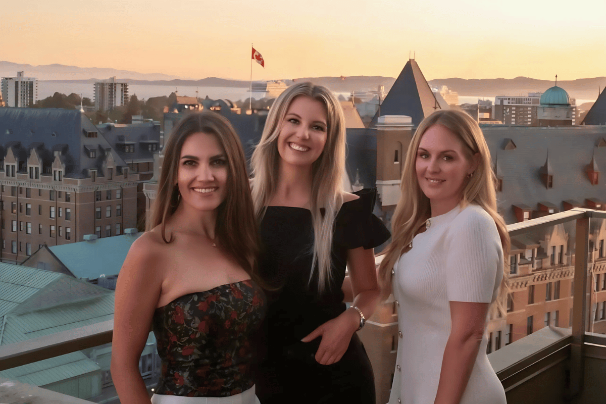 The Coastal Living Collective team posing on a rooftop with a stunning view of Victoria’s skyline, exemplifying the charm of coastal living and real estate expertise.