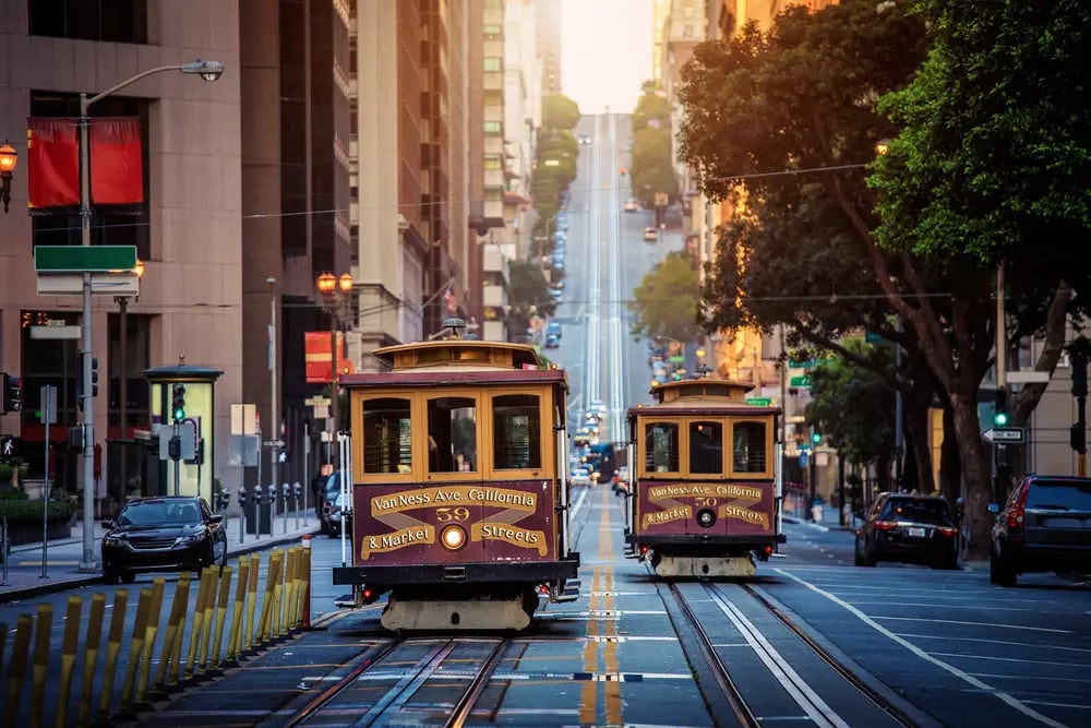 Two historic cable cars on California Street in downtown San Francisco at golden hour sunset