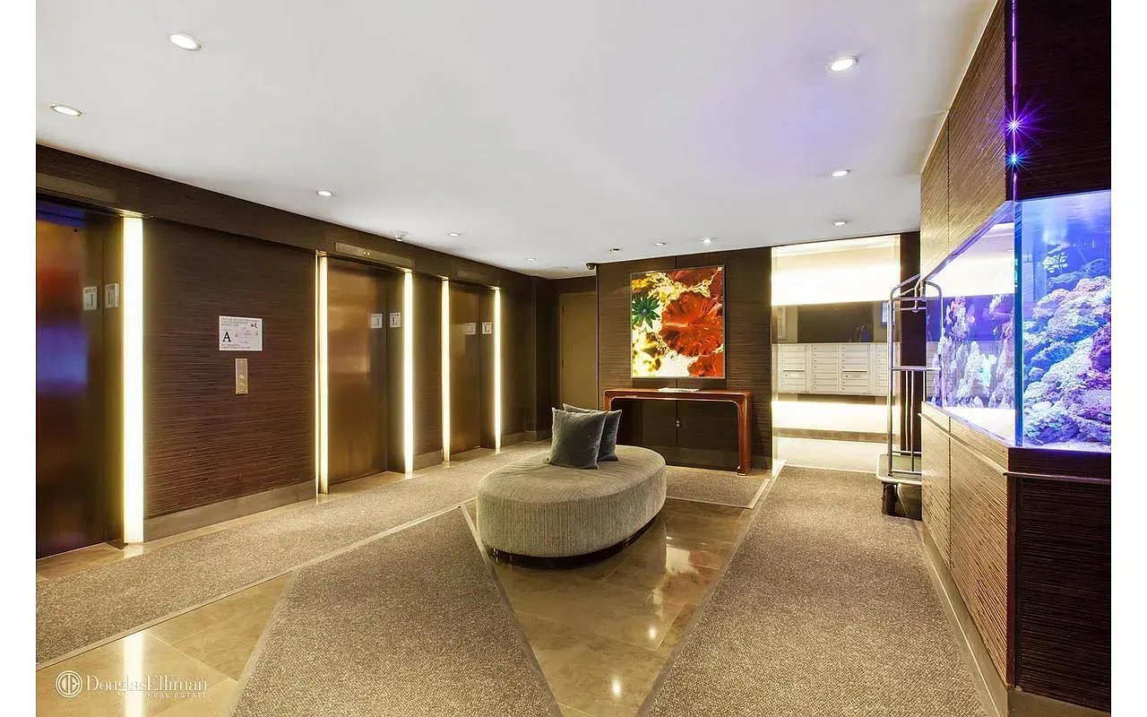 Building lobby with elevator doors, a curved bench, and a brightly lit aquarium.
