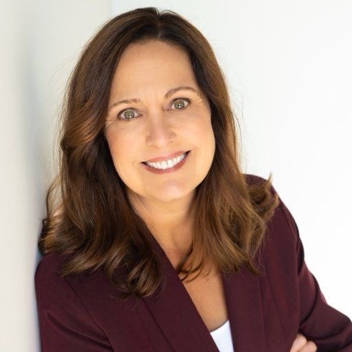 Lorie Bredeson smiling in a burgundy blazer.