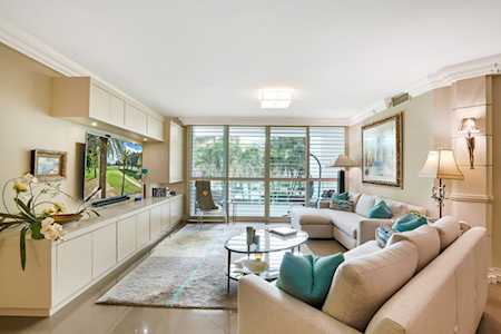 Living room with cream sofas, teal cushions, built-in cabinetry, and sliding doors to a leafy balcony.