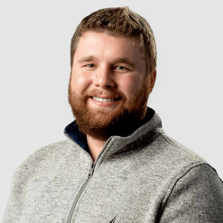 Sebastien Sommer, smiling in a gray zip-up sweater.