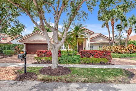 Single-story home with a red tile roof, brick driveway, and landscaped front yard.