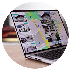 Laptop displaying home listings and a map on a real estate website.