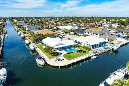 Aerial view of canal-front homes with private docks, boats, and a backyard pool.
