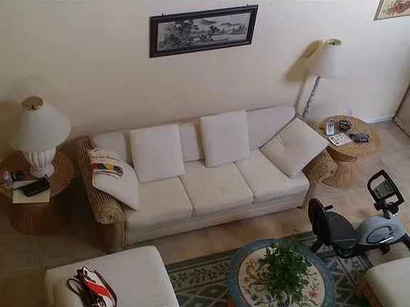 Living room with a white sofa, wicker side tables, and a round coffee table on a patterned rug.