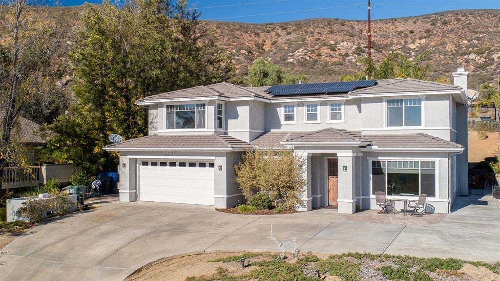 Two-story gray home with solar panels, a three-car garage, and a broad driveway.