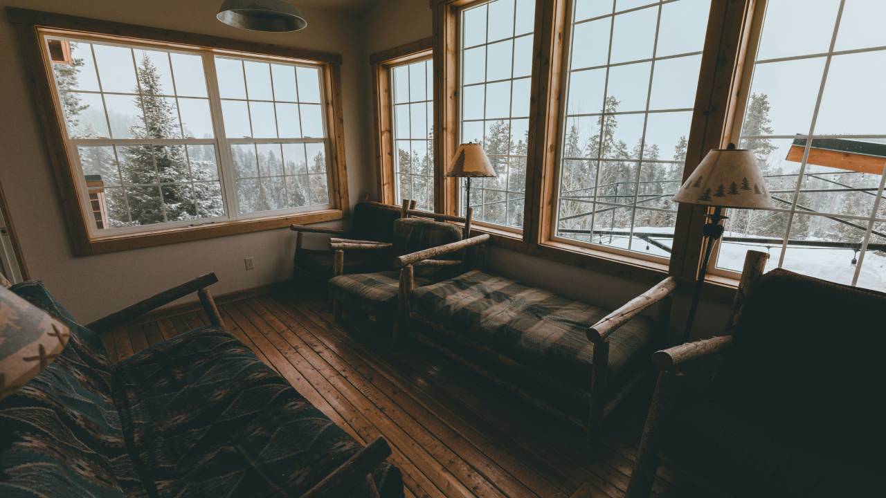 Cozy mountain cabin interior with large windows and snowy views, ideal for staging when selling your Aspen property in winter.
