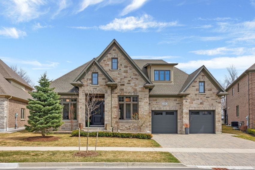 Stone home with multiple gables, two garage doors, and a paved front driveway.