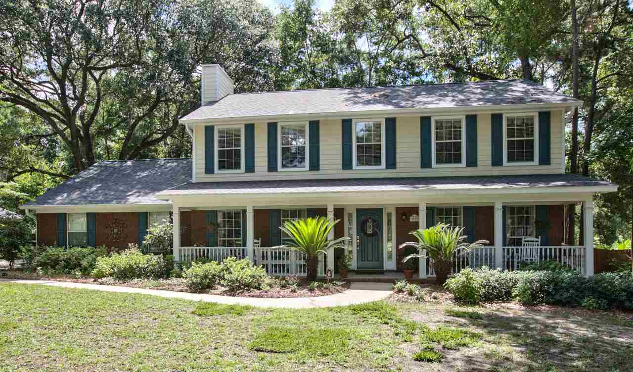 A cozy home nestled in a wooded area, surrounded by lush trees and green grass.