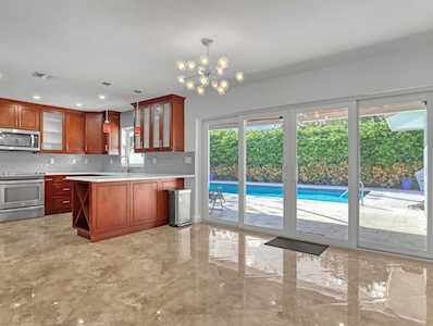 Kitchen with cherry cabinetry and island opening to a poolside patio.