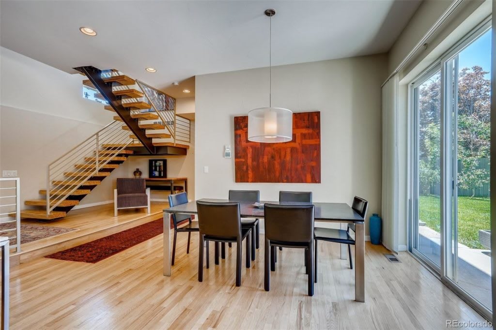 Dining area with a modern staircase, dark table, and sliding glass doors to the yard.