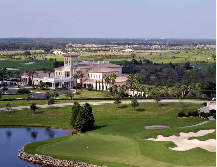 Golf course and clubhouse with a pond and sand bunkers in the foreground.