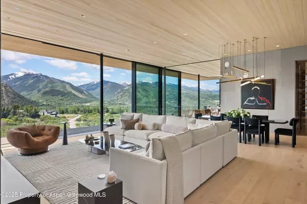 Modern living room with a white sectional and floor-to-ceiling mountain views.
